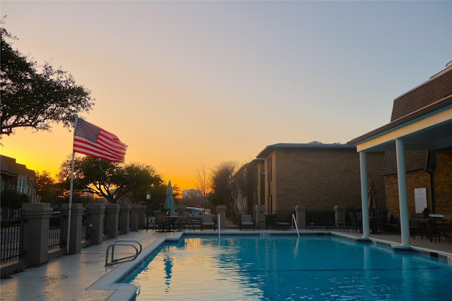 pool at dusk with a patio area