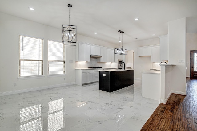 kitchen featuring gas cooktop, backsplash, white cabinets, and hanging light fixtures