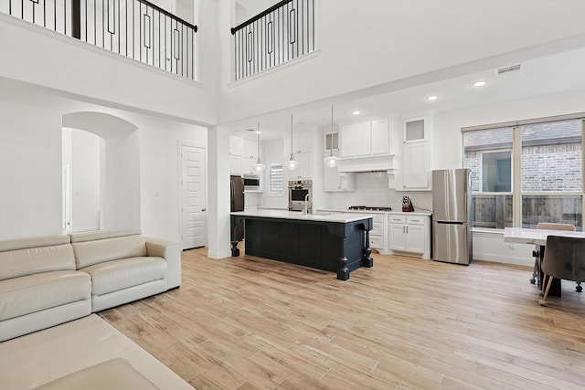 living room featuring a towering ceiling, sink, and light hardwood / wood-style flooring