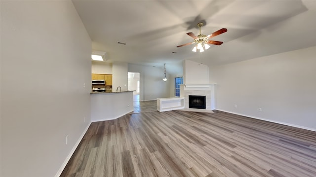 unfurnished living room featuring ceiling fan, a tile fireplace, and light hardwood / wood-style flooring