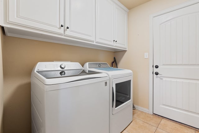 clothes washing area with cabinet space, independent washer and dryer, baseboards, and light tile patterned flooring