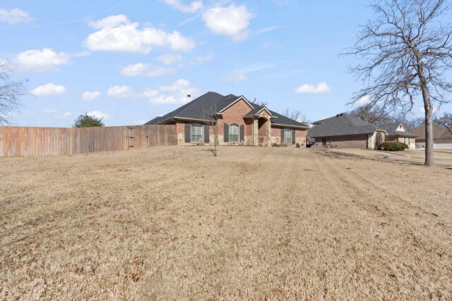 view of front facade with a front yard, brick siding, and fence