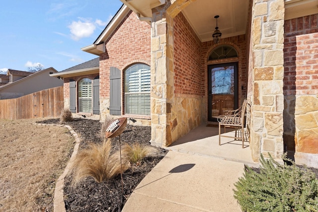 entrance to property with stone siding, fence, and brick siding