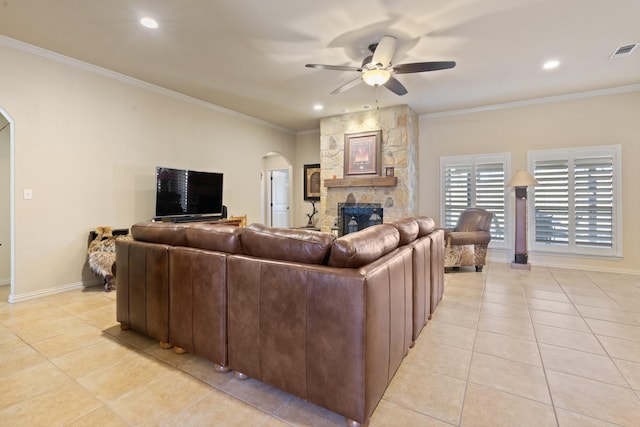 living area featuring arched walkways, light tile patterned floors, a fireplace, visible vents, and crown molding