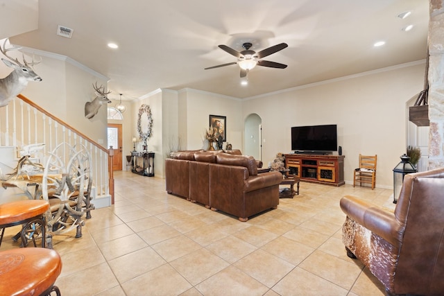 living area with light tile patterned floors, ceiling fan, stairs, and arched walkways