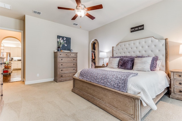 carpeted bedroom featuring a spacious closet, stainless steel fridge, and ceiling fan