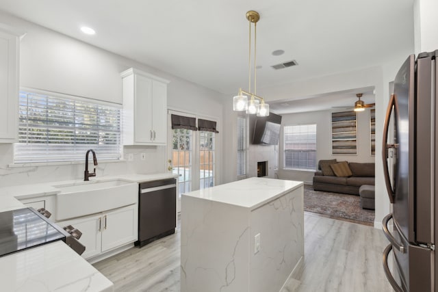 kitchen featuring light stone countertops, hanging light fixtures, white cabinets, and stainless steel appliances