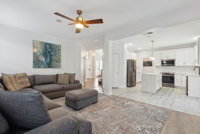 living room with light wood-type flooring and ceiling fan