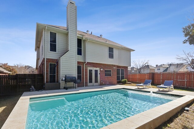 rear view of house featuring a fenced in pool, a patio area, and french doors