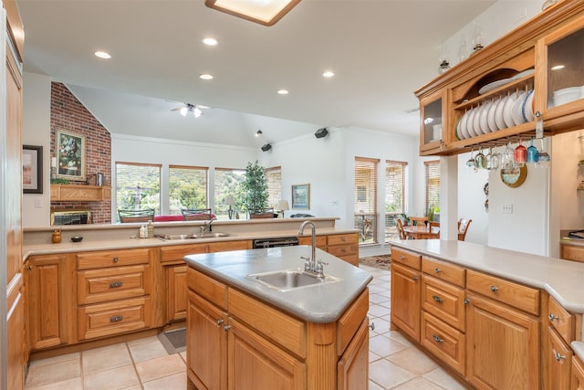 kitchen featuring kitchen peninsula, vaulted ceiling, sink, a fireplace, and an island with sink