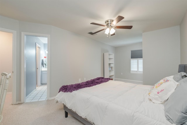 carpeted bedroom with ensuite bath and ceiling fan