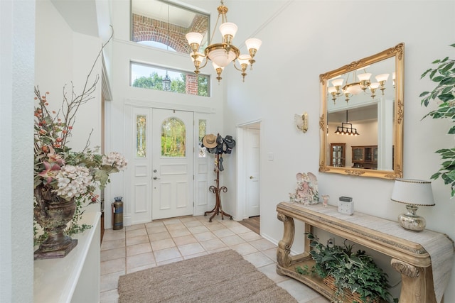 foyer entrance with a towering ceiling, light tile patterned floors, and an inviting chandelier