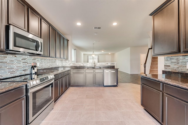 kitchen with dark brown cabinetry, light tile patterned flooring, pendant lighting, and appliances with stainless steel finishes