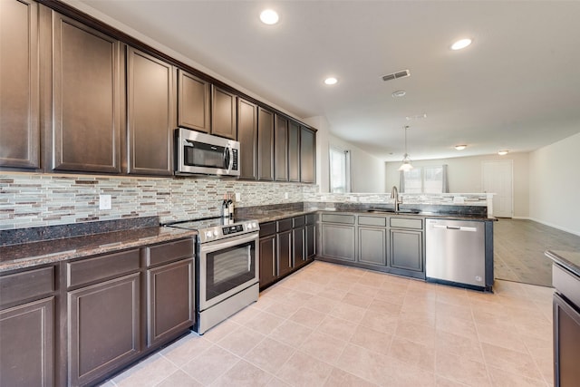 kitchen featuring sink, decorative light fixtures, dark brown cabinets, kitchen peninsula, and stainless steel appliances