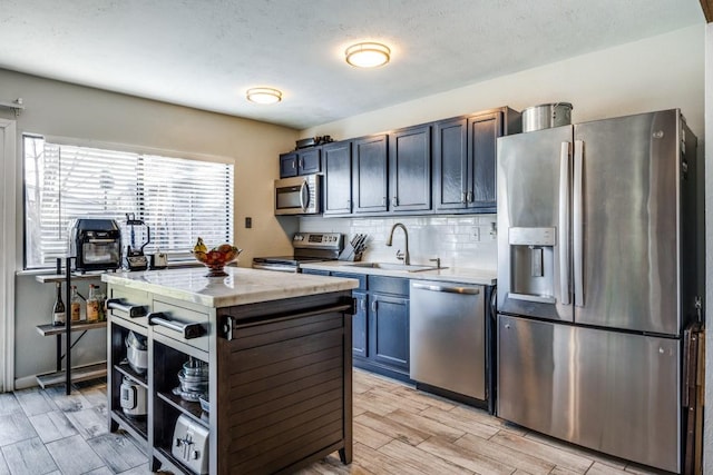 kitchen featuring backsplash, sink, light hardwood / wood-style flooring, appliances with stainless steel finishes, and a kitchen island