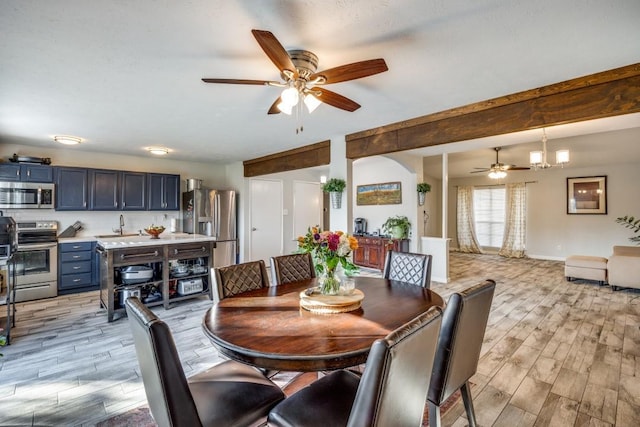 dining space featuring beamed ceiling, ceiling fan with notable chandelier, and sink