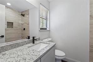 bathroom featuring vanity, toilet, and tiled shower