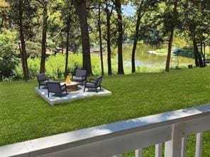 view of home's community with a water view, a yard, and an outdoor fire pit