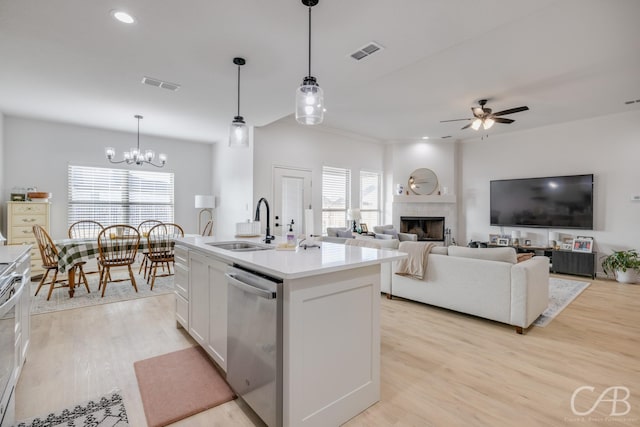 kitchen featuring stainless steel dishwasher, ceiling fan with notable chandelier, a kitchen island with sink, decorative light fixtures, and white cabinetry