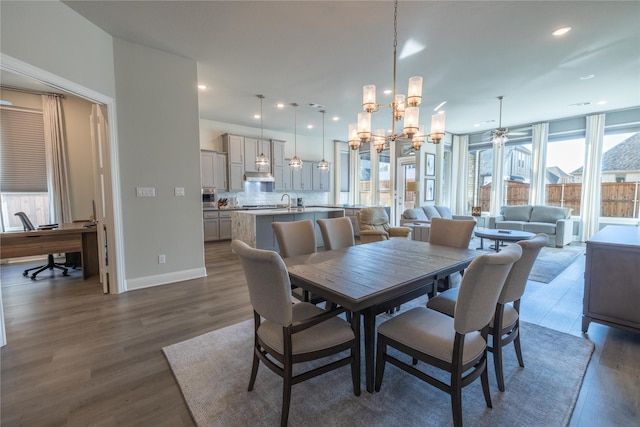 dining area featuring dark hardwood / wood-style flooring and ceiling fan with notable chandelier