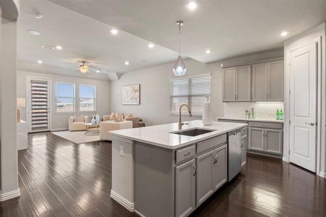 kitchen featuring pendant lighting, an island with sink, sink, gray cabinetry, and stainless steel dishwasher