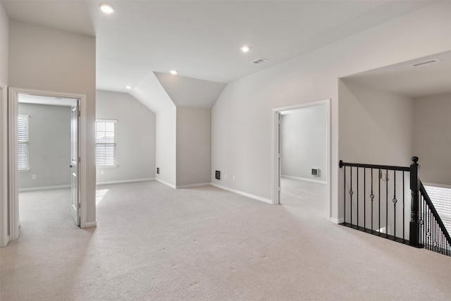 bonus room with vaulted ceiling and light carpet