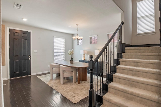 entryway with dark wood-type flooring and a chandelier