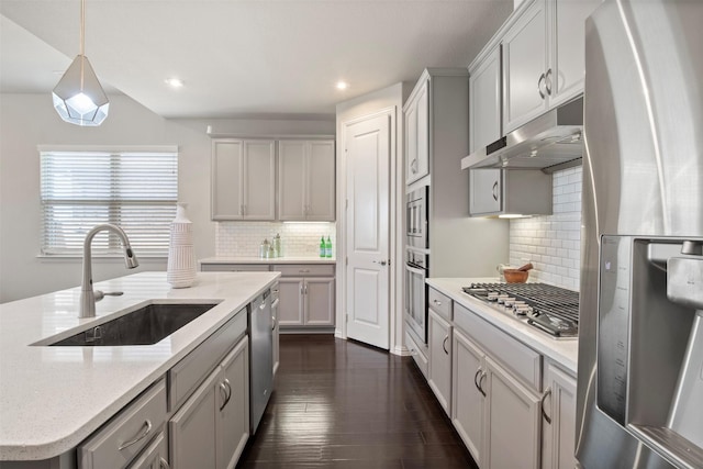 kitchen with sink, light stone counters, decorative light fixtures, dark hardwood / wood-style floors, and stainless steel appliances