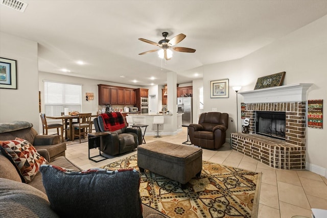 tiled living room featuring ceiling fan and a brick fireplace