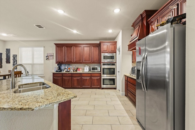 kitchen featuring light stone countertops, tasteful backsplash, stainless steel appliances, sink, and light tile patterned floors