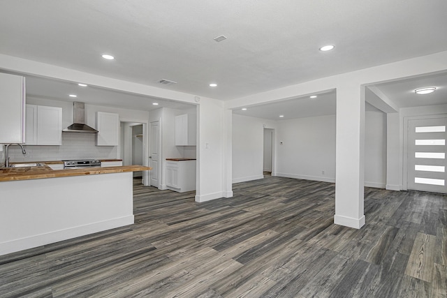 kitchen with sink, wall chimney range hood, wood counters, electric stove, and white cabinets