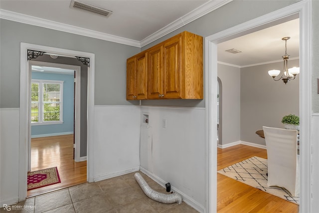 laundry area featuring washer hookup, crown molding, light hardwood / wood-style floors, and cabinets