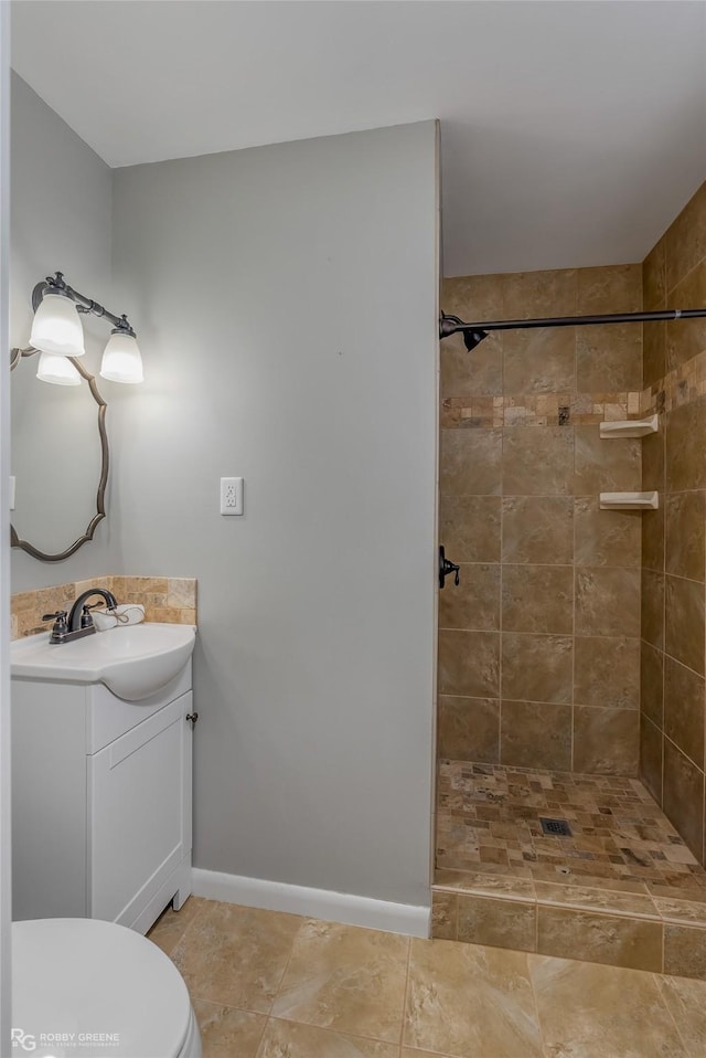 bathroom with tiled shower, vanity, toilet, and tile patterned flooring