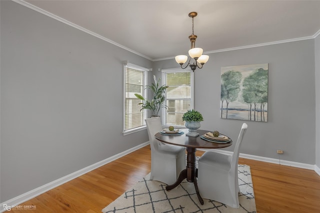 dining space featuring an inviting chandelier, ornamental molding, and light wood-type flooring