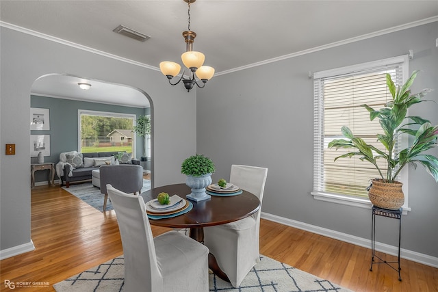 dining room featuring crown molding, an inviting chandelier, and light hardwood / wood-style floors