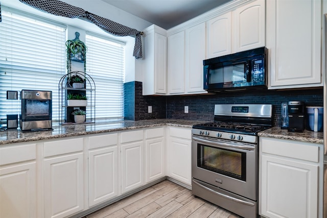 kitchen featuring white cabinets, gas stove, tasteful backsplash, and dark stone counters