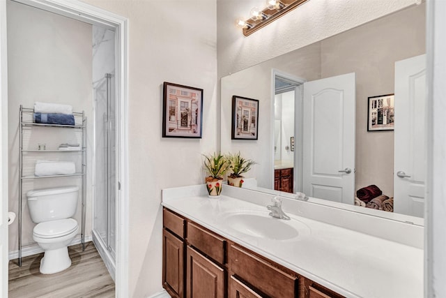 bathroom featuring hardwood / wood-style floors, vanity, a shower with door, and toilet