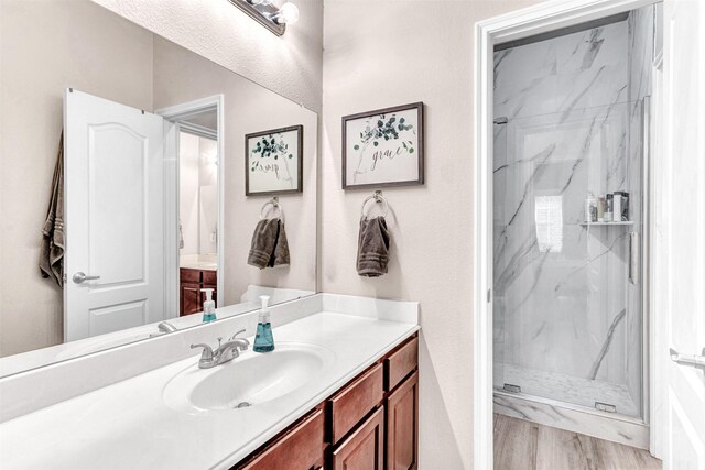 bathroom featuring tiled shower, wood-type flooring, and vanity