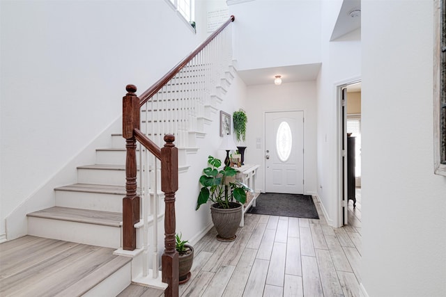 foyer featuring plenty of natural light, light wood-type flooring, and a towering ceiling