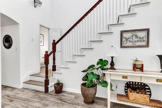 stairway with a high ceiling and hardwood / wood-style flooring