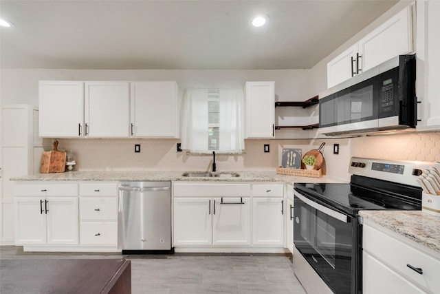 kitchen with tasteful backsplash, light stone counters, stainless steel appliances, sink, and white cabinetry