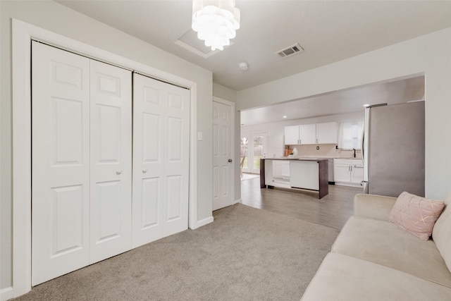 carpeted living room featuring a notable chandelier and sink