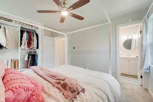 bedroom featuring ensuite bathroom, sink, ceiling fan, light colored carpet, and a closet