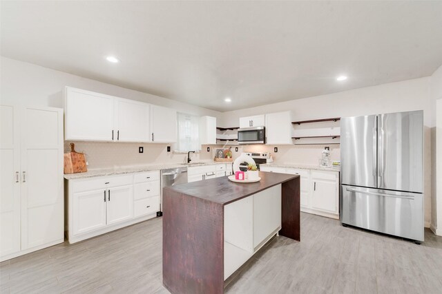 kitchen featuring white cabinetry, a center island, sink, stainless steel appliances, and butcher block countertops