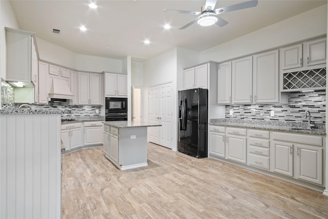 kitchen featuring custom exhaust hood, black appliances, white cabinets, sink, and a kitchen island