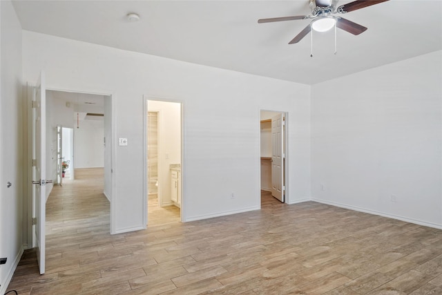 unfurnished bedroom with ensuite bathroom, ceiling fan, a walk in closet, and a closet