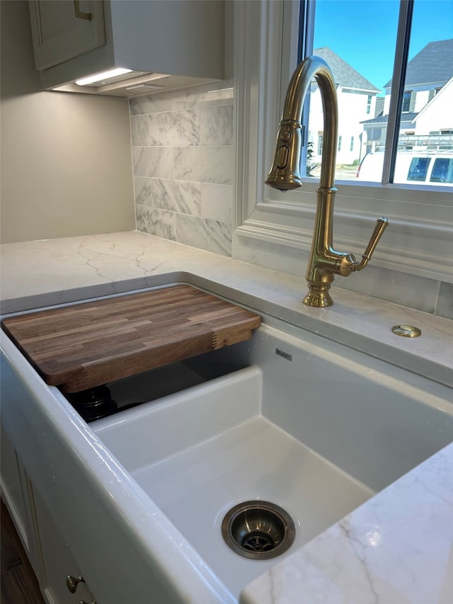 details featuring decorative backsplash, light stone countertops, and a sink