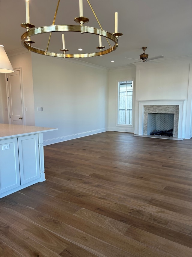 unfurnished living room featuring dark wood finished floors, a fireplace, baseboards, and ornamental molding