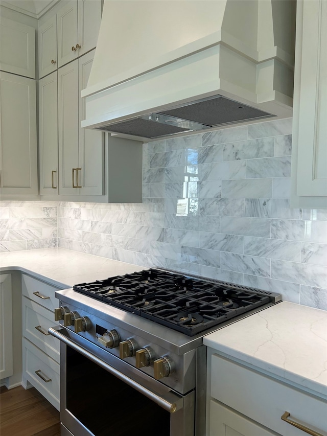 kitchen with decorative backsplash, custom exhaust hood, light stone countertops, and high end stainless steel range oven