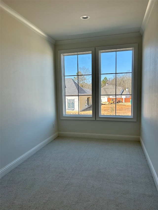 carpeted spare room featuring baseboards, a healthy amount of sunlight, and ornamental molding